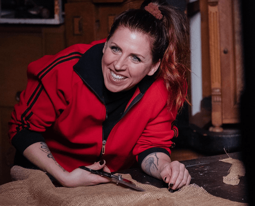 Frau in roter Jacke arbeitet lächelnd an einem DIY-Projekt in Werkstattfürschönes Düsseldorf