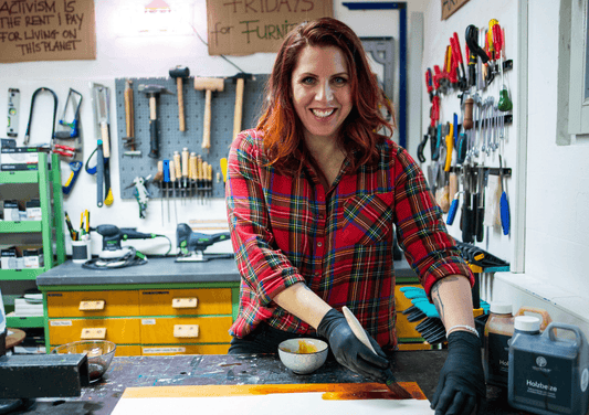 Frau in Werkstatt in Düsseldorf-Gerresheim streicht Holz, umgeben von Werkzeugen, bei DIY-Workshop