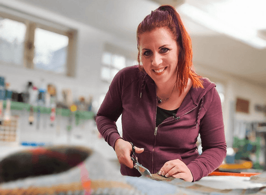 Frau beim Zuschneiden von Stoff in heller Werkstatt, Handwerks-Workshop Düsseldorf