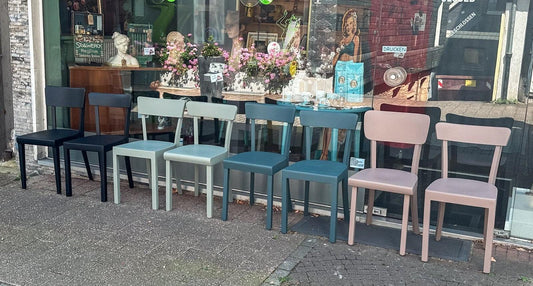 Mehrere neu lackierte Holzstühle in verschiedenen Farben vor Werkstattfürschönes Düsseldorf