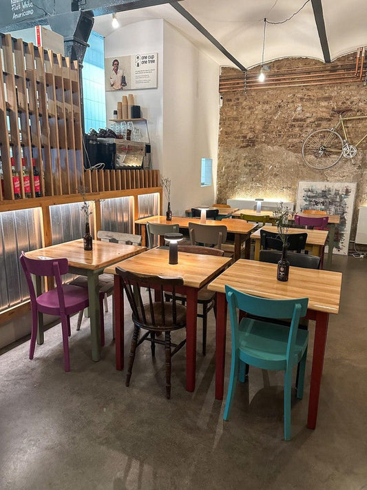Gemütliches Café mit bunten Stühlen, Holztischen und Vintage-Deko in Düsseldorf-Gerresheim.